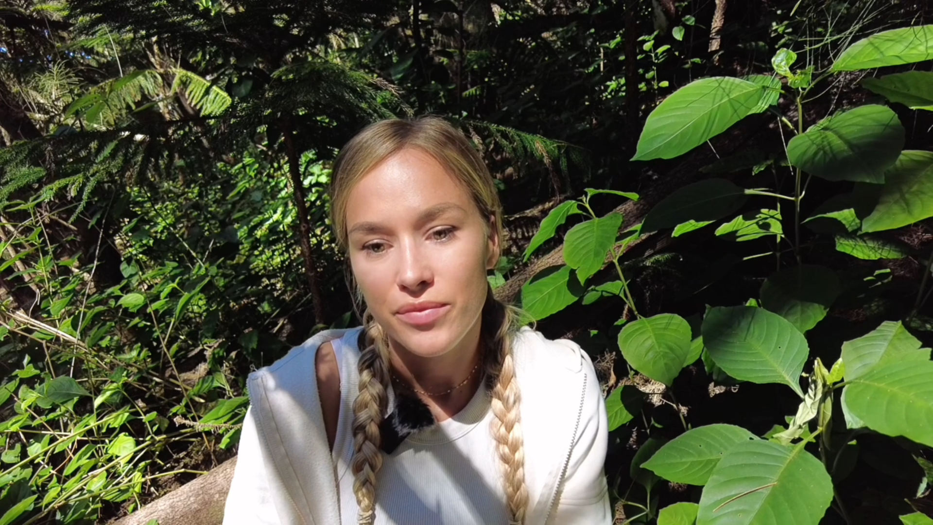 Kseniya surrounded by sunlit forest greenery
